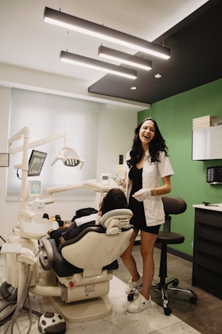 a woman standing next to a person in a dental chair