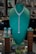 A jewelry display in a store showcases a set of jewelry with blue gemstone accents. The centerpiece is an elegant necklace with a heart-shaped design and matching earrings. The pieces are presented on a green velvet display stand, giving a luxurious and sophisticated appearance.