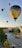 A vibrant hot air balloon ascending gently over the cityscape at dawn.
