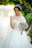 Bride smiling happily wearing a delicate floral hairpiece during a sunny outdoor ceremony.
