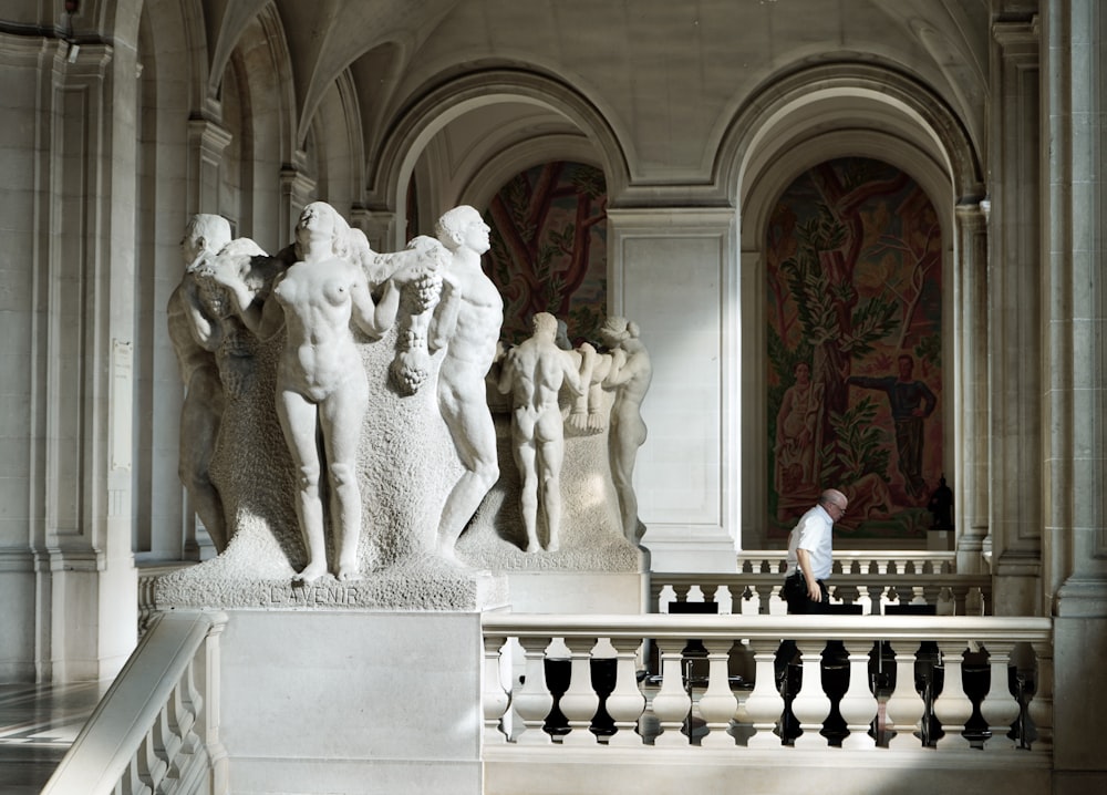 a person sitting on a bench in front of a group of statues