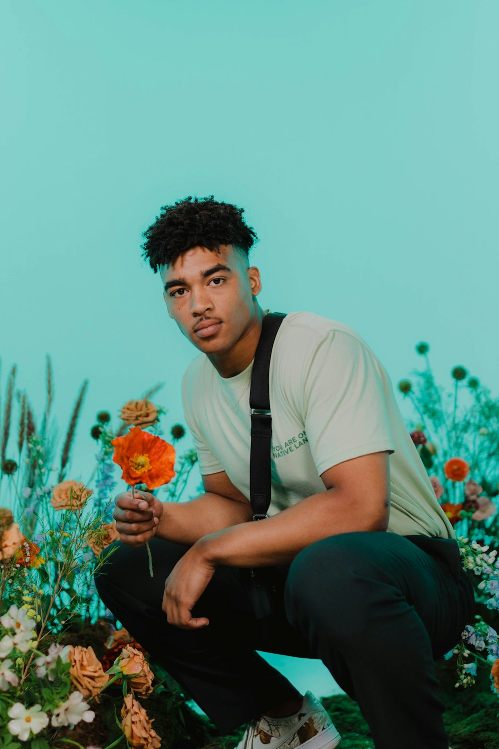 a man sitting on a rock holding a flower