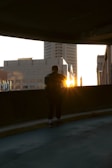 Sunset view over the city skyline with a person wearing Suzuki Apparel standing on a rooftop.
