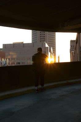 Sunset view over the city skyline with a person wearing Suzuki Apparel standing on a rooftop.