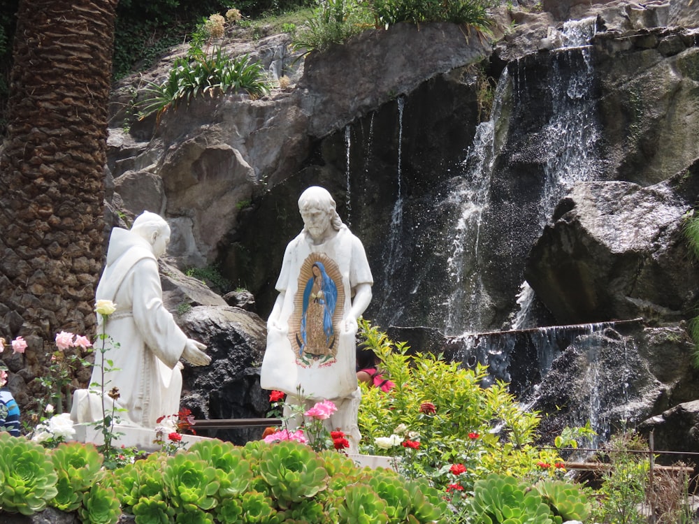 a group of statues in front of a waterfall