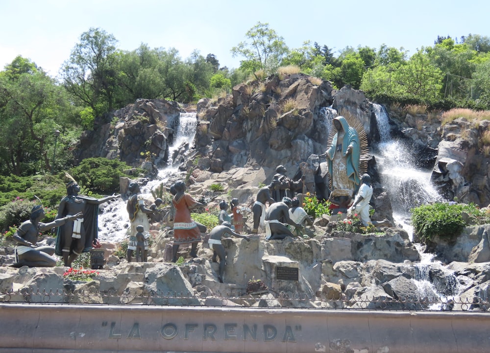 a group of statues in front of a waterfall