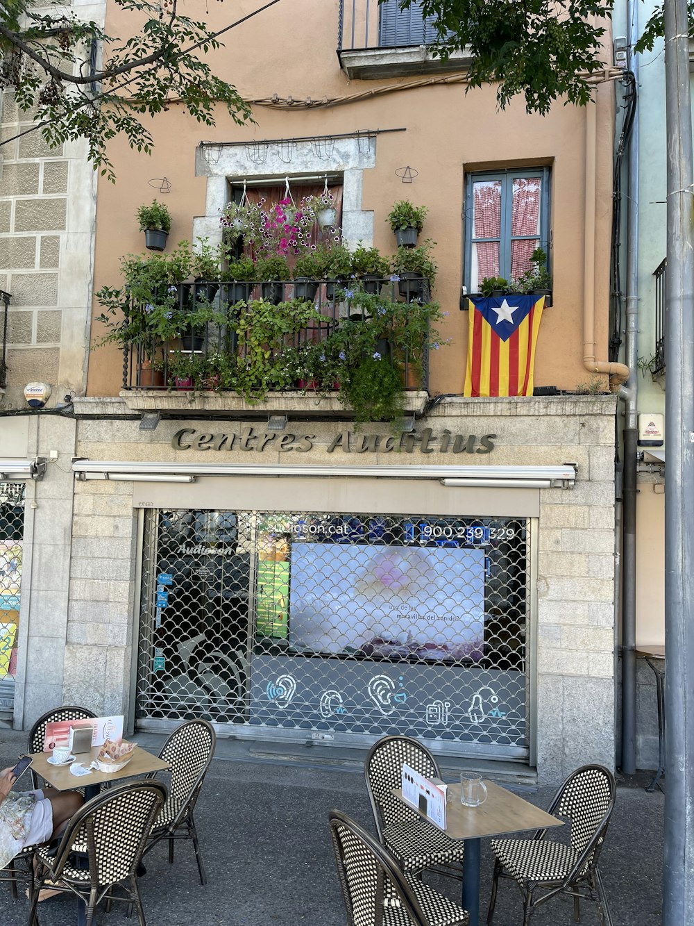 a patio with tables and chairs outside a building with a flag on the wall