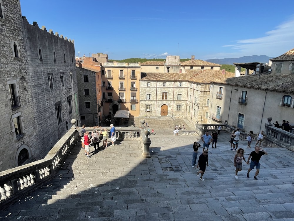 a group of people walking around a courtyard with buildings around it