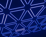 A glowing network grid spreading across a dark surface, representing the execution of reality.