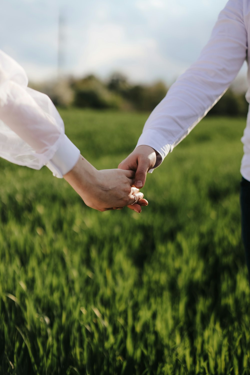 a couple of hands holding a small white object in a grassy area