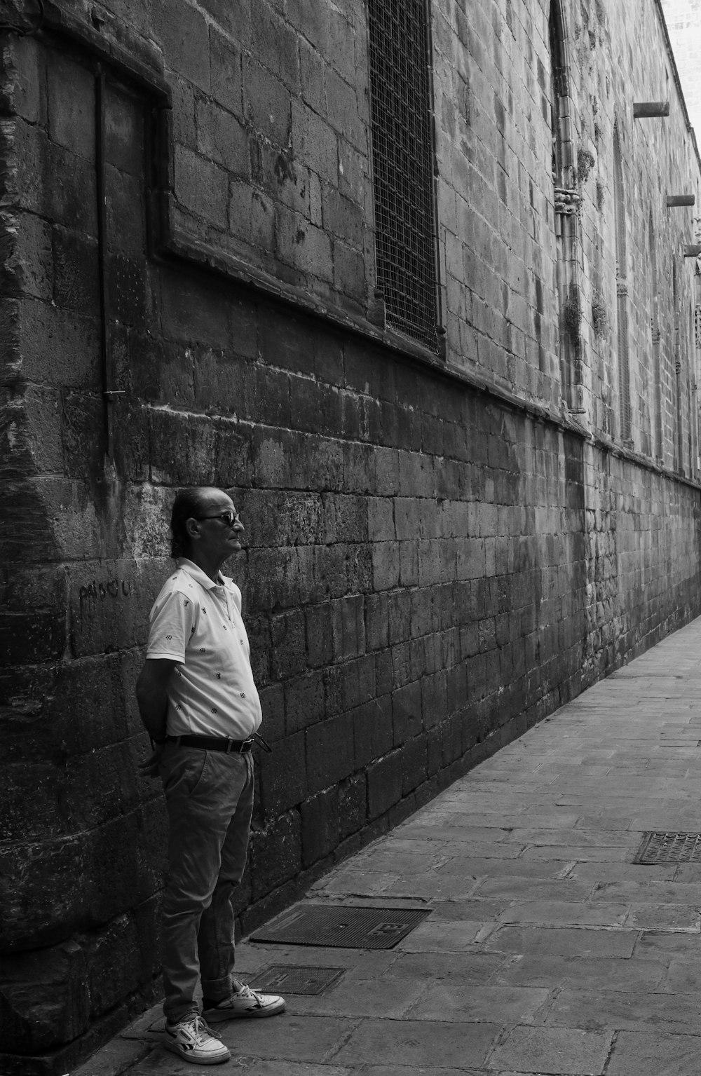 a man standing next to a brick wall