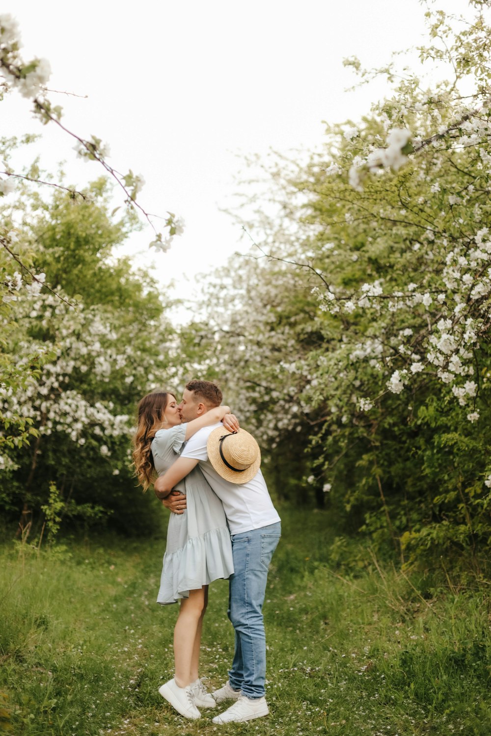 a man and woman kissing in front of a flowering tree