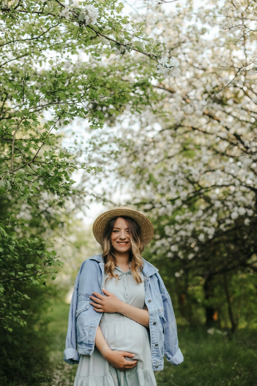 a person wearing a hat and standing under a flowering tree