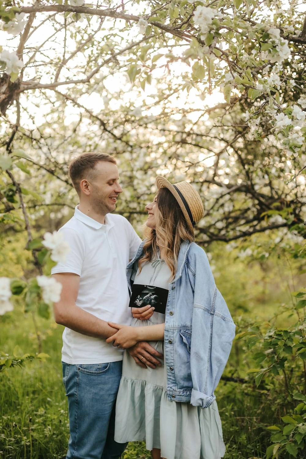 a man and woman standing under a tree with white flowers