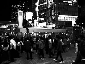 A bustling city street scene with people walking and lights glowing.