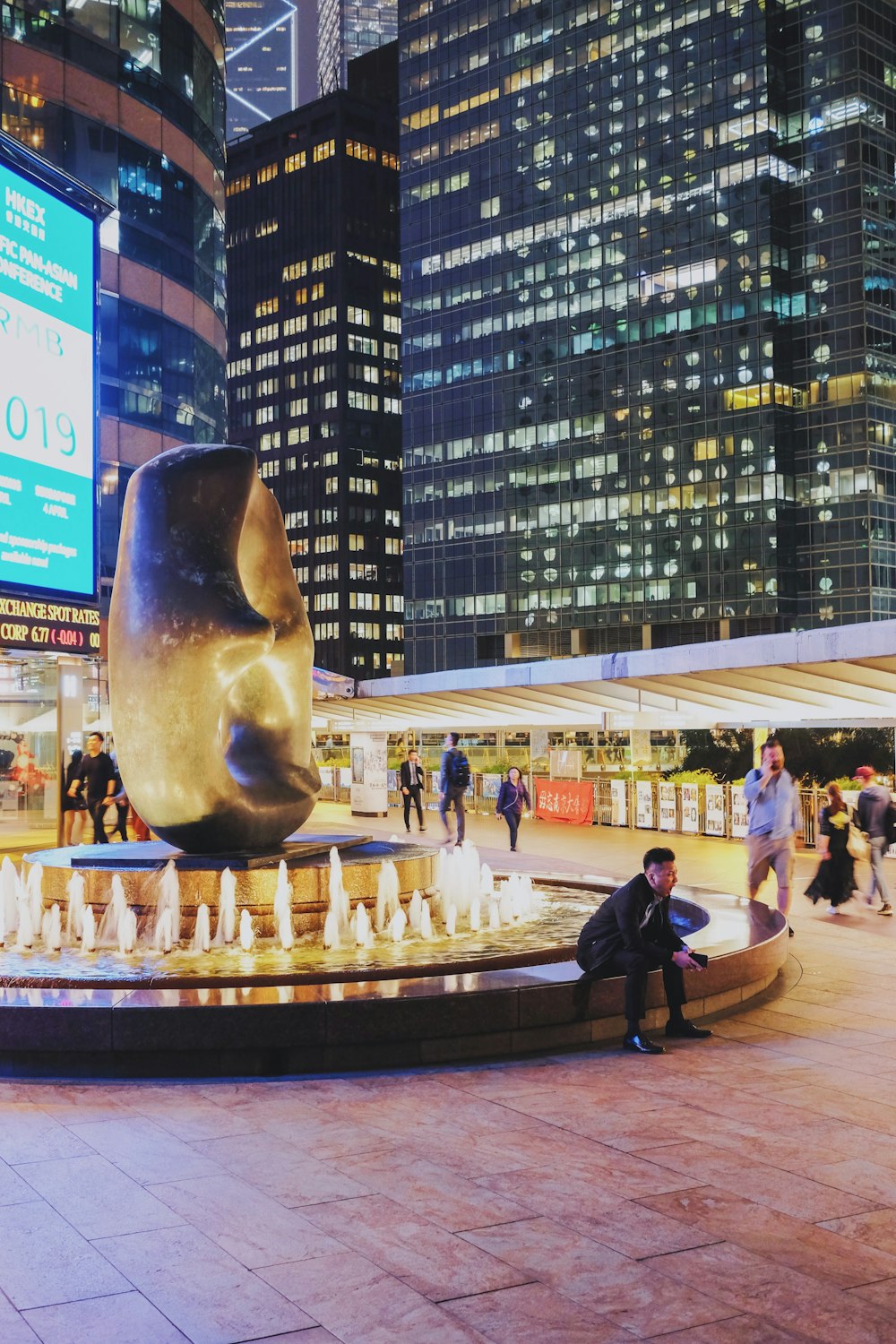 a person sitting on a bench next to a large statue of a bear