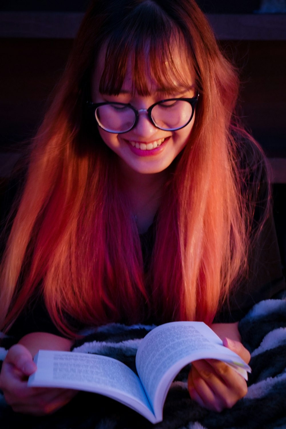 a person with red hair and glasses holding a book