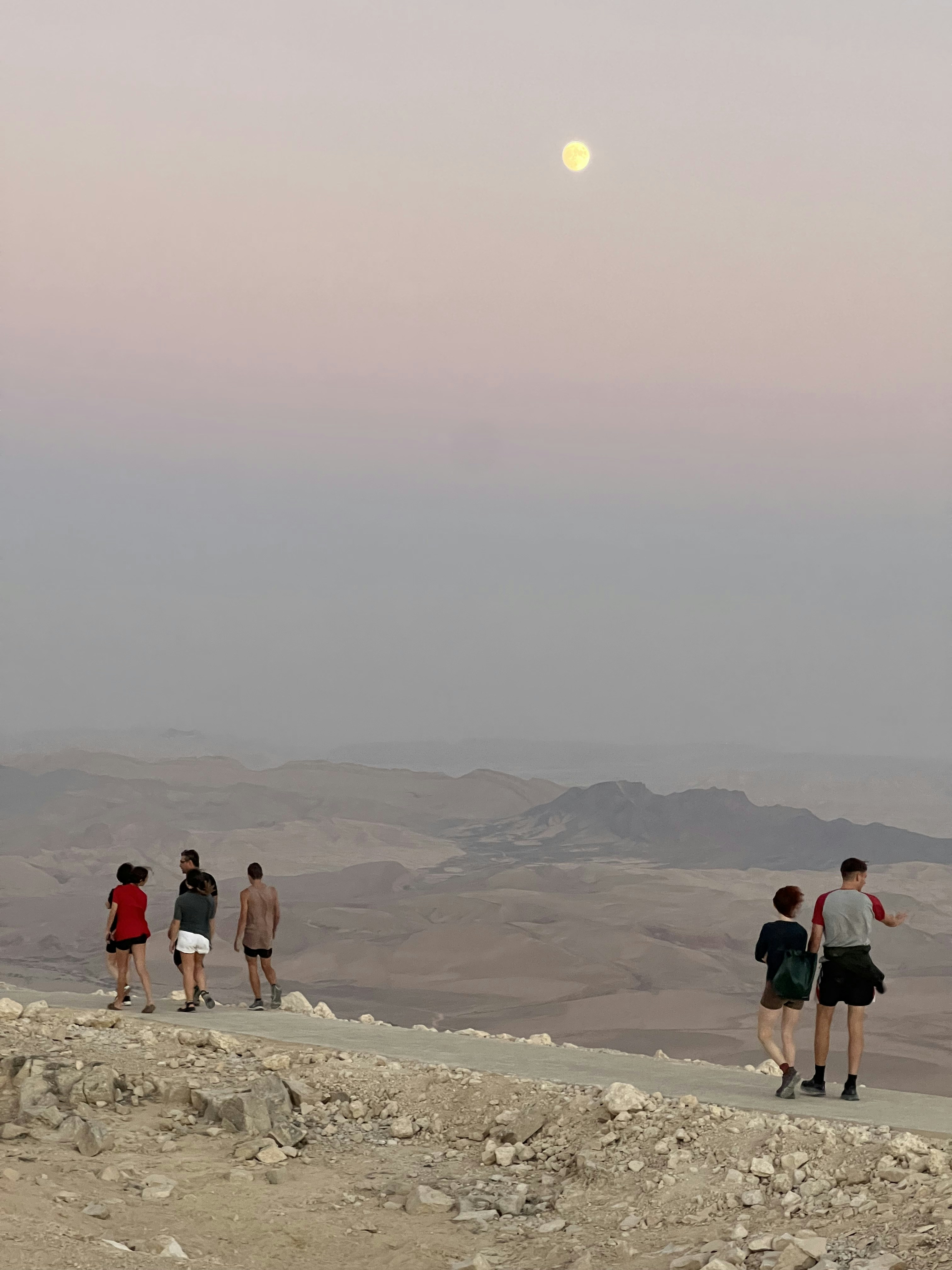空に月がある岩だらけの丘の上を歩く人々のグループの写真 Unsplashのミツペ・ラモンの無料画像