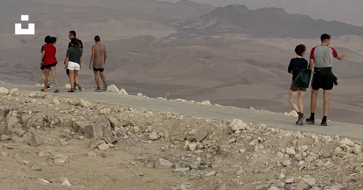 空に月がある岩だらけの丘の上を歩く人々のグループの写真 Unsplashのミツペ・ラモンの無料画像