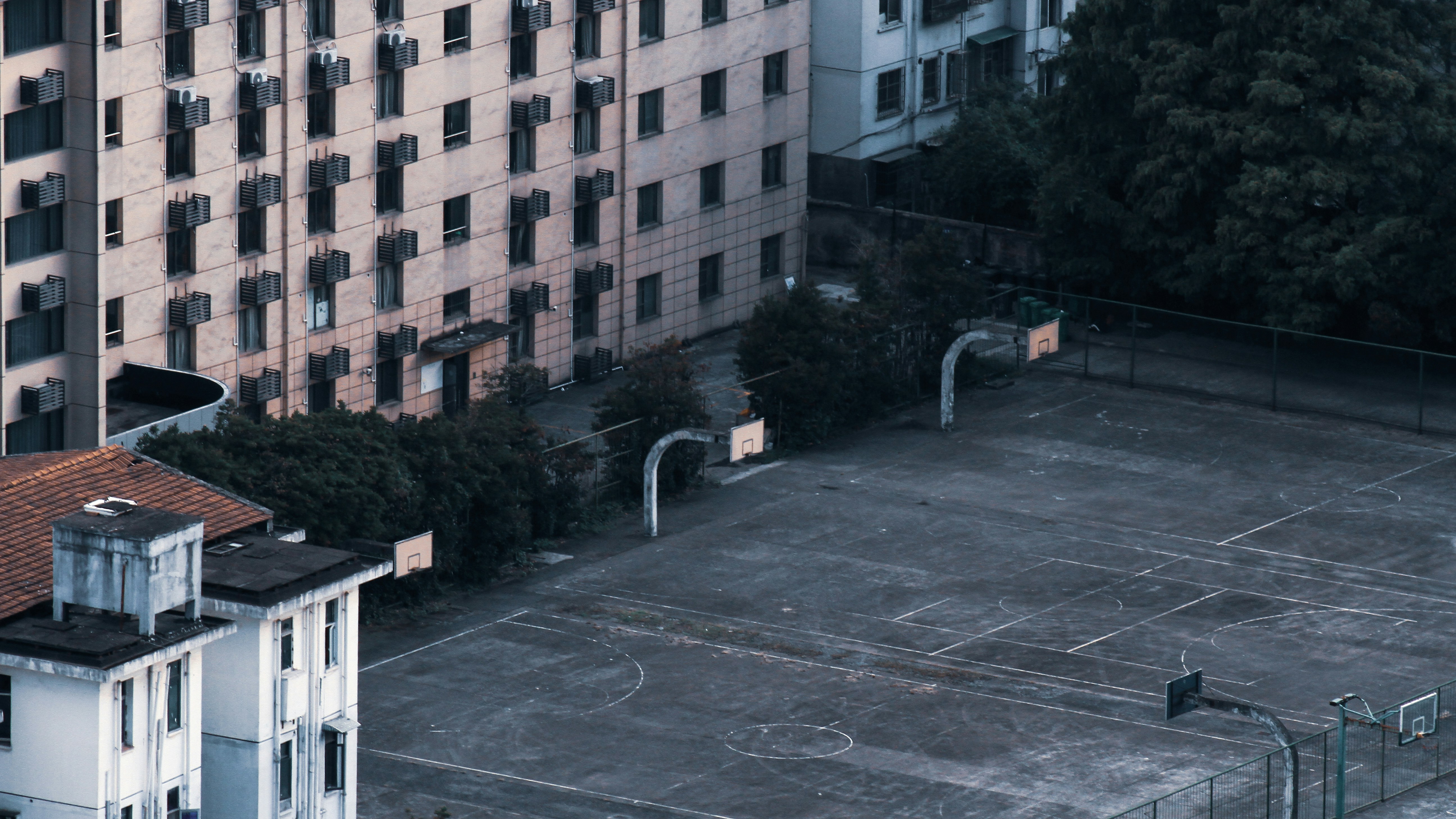 a building with a fence and trees in the front