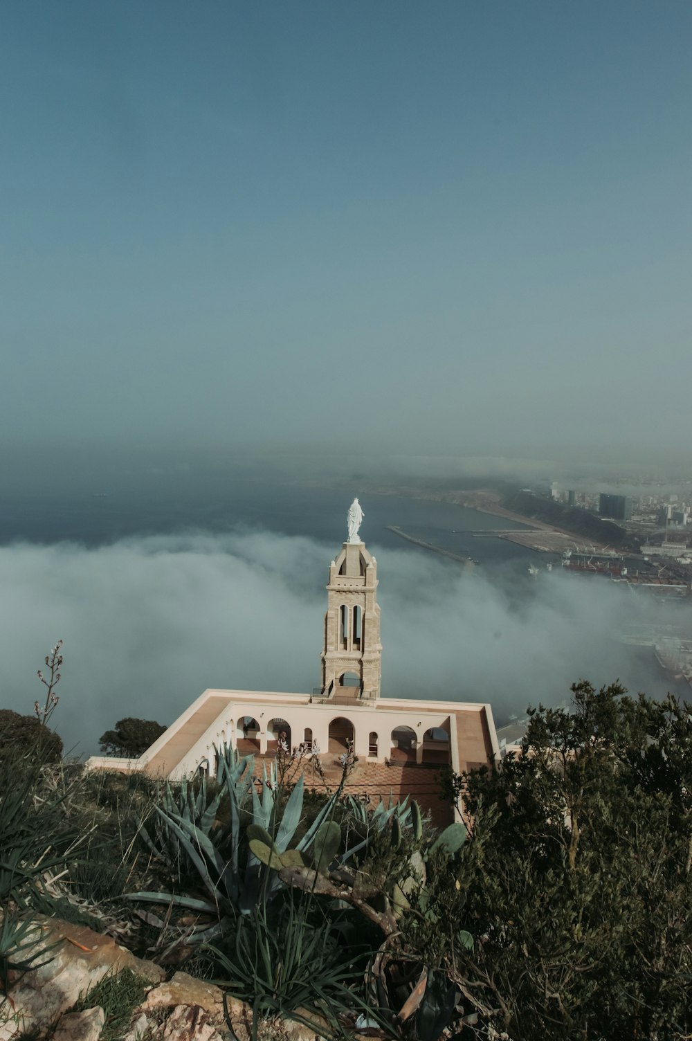 a white building with a tower and a foggy city in the background