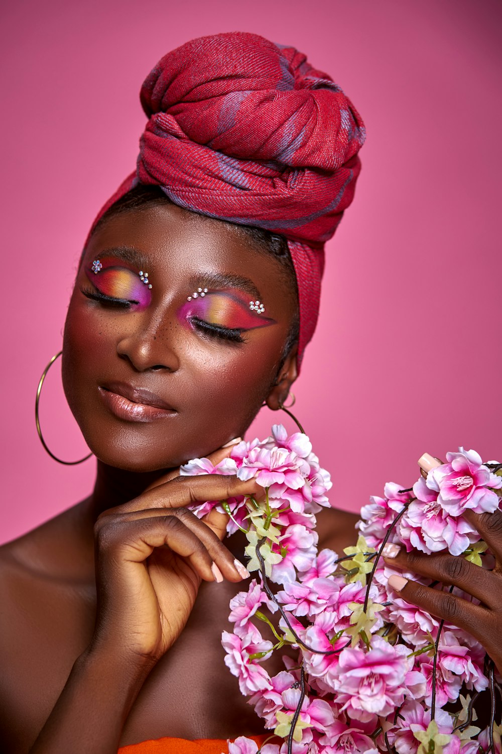 a woman in a red turban with pink flowers