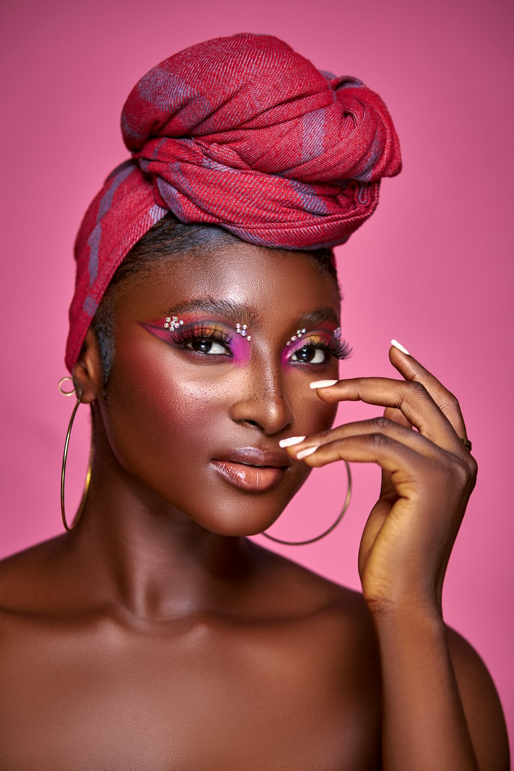 a woman wearing a red turban and pink makeup