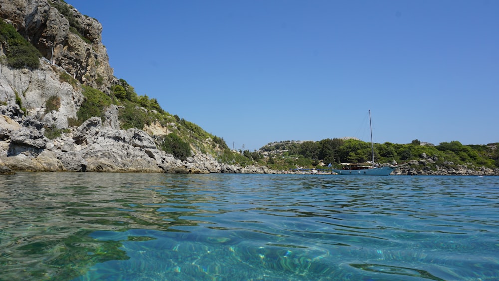 a body of water with a boat in it and rocky hills in the background