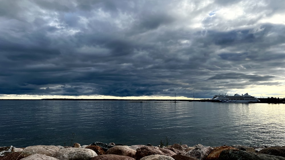 a rocky shore with a body of water and a cloudy sky