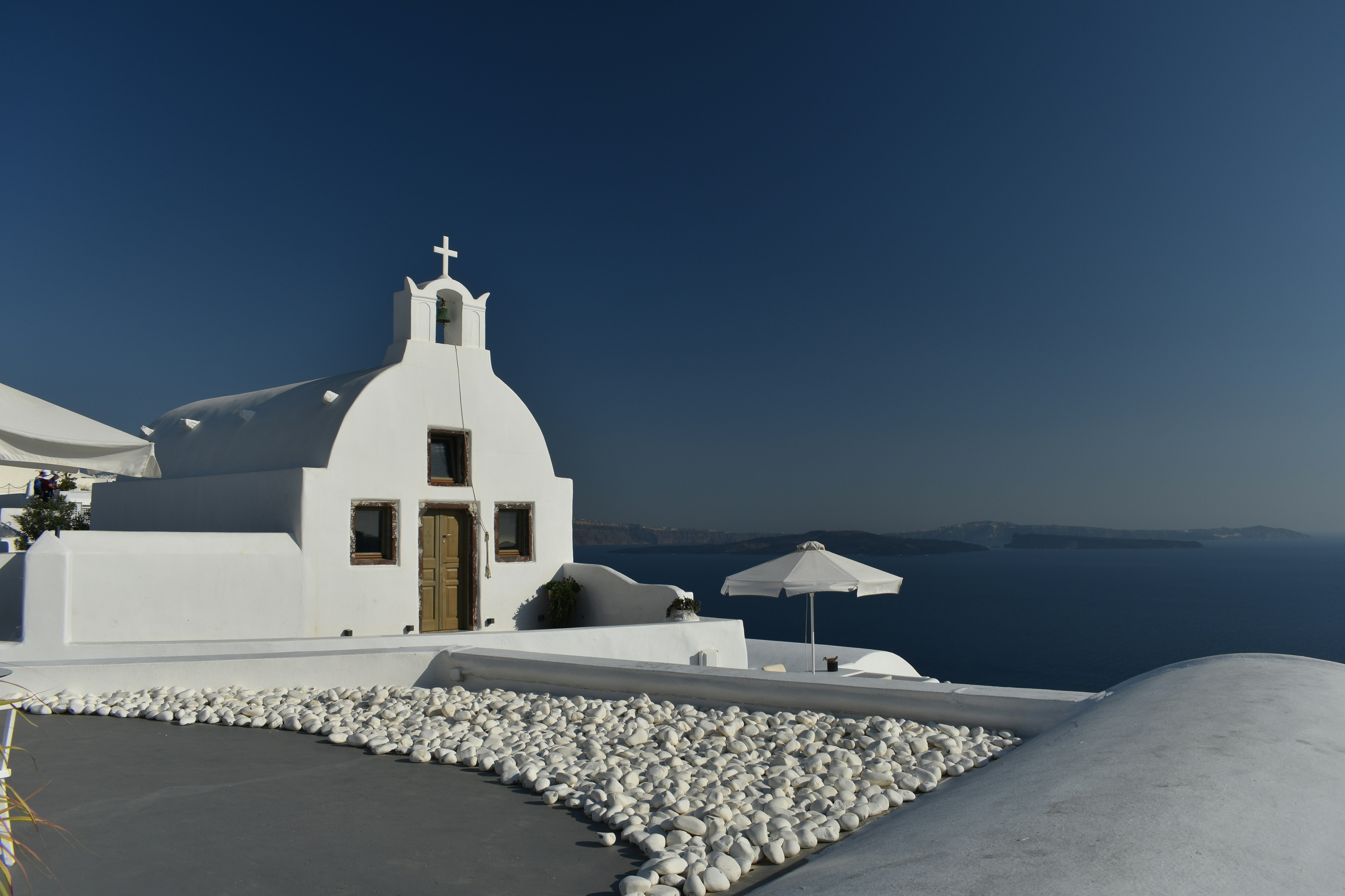 a white building with a cross on top of it by the water
