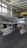 A metallic aircraft featuring a distinctive design with two drop tanks under the wings is inside a hangar. The aircraft showcases a polished, reflective surface with markings. The hangar has a high ceiling with large windows allowing natural light to illuminate the space.