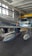 A metallic aircraft featuring a distinctive design with two drop tanks under the wings is inside a hangar. The aircraft showcases a polished, reflective surface with markings. The hangar has a high ceiling with large windows allowing natural light to illuminate the space.