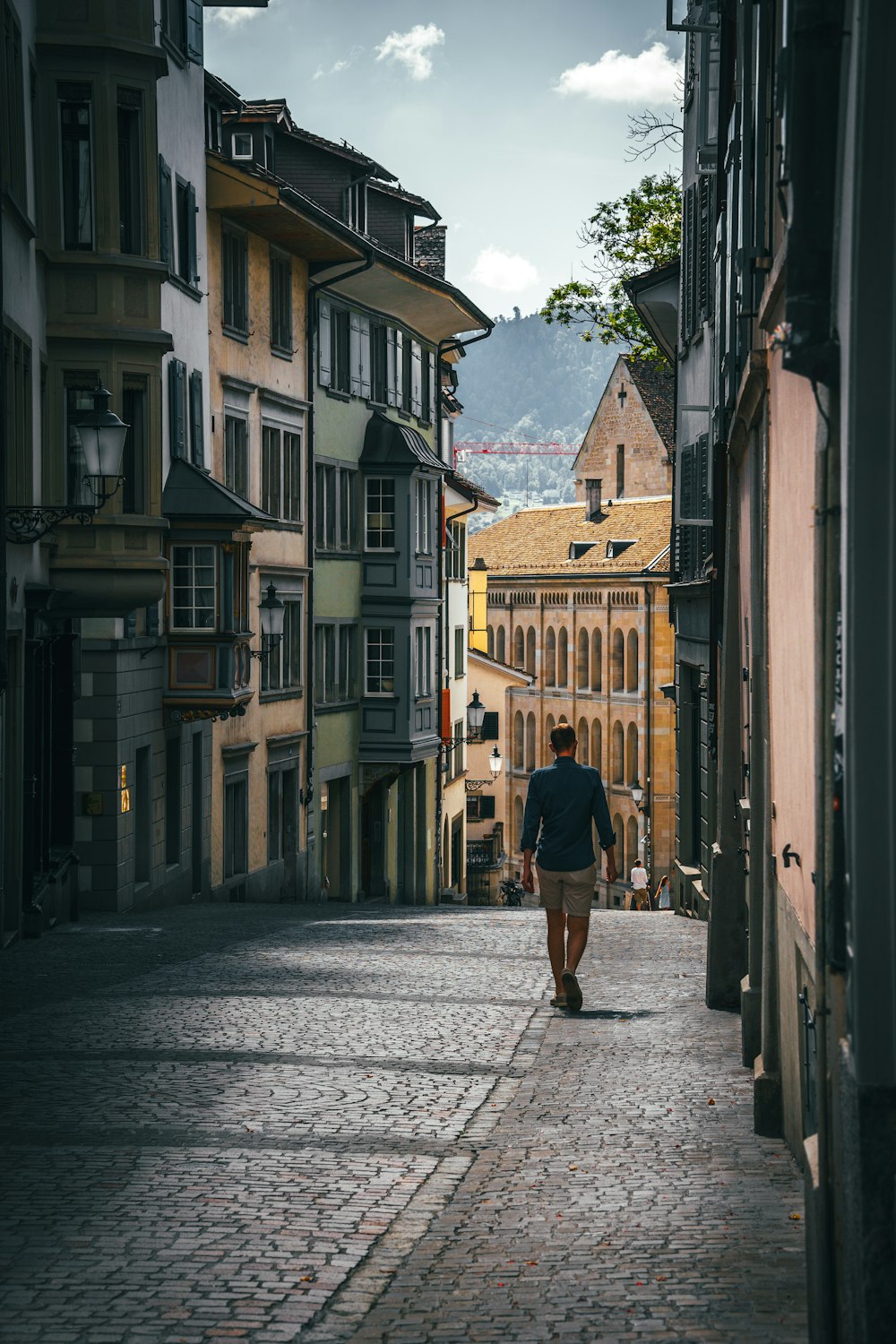 une personne marchant dans une rue pavée entre des bâtiments