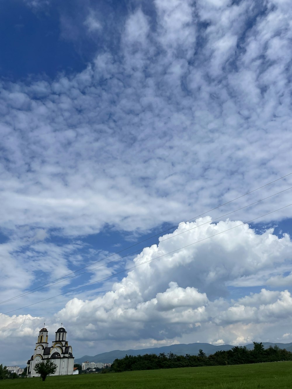 Un grand bâtiment blanc avec une tour et un ciel nuageux au-dessus