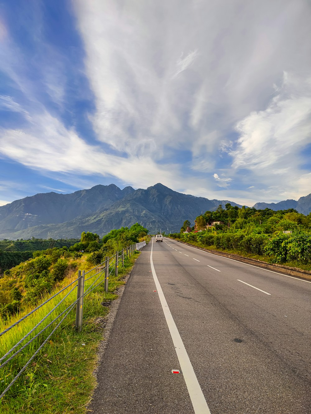 a road with trees and mountains on the side