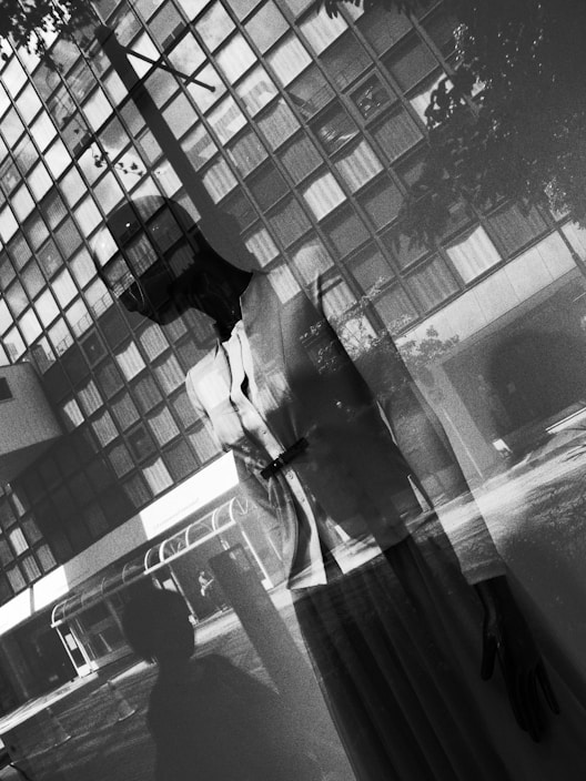 A sleek, minimalistic city outfit displayed on a mannequin against a soft urban backdrop