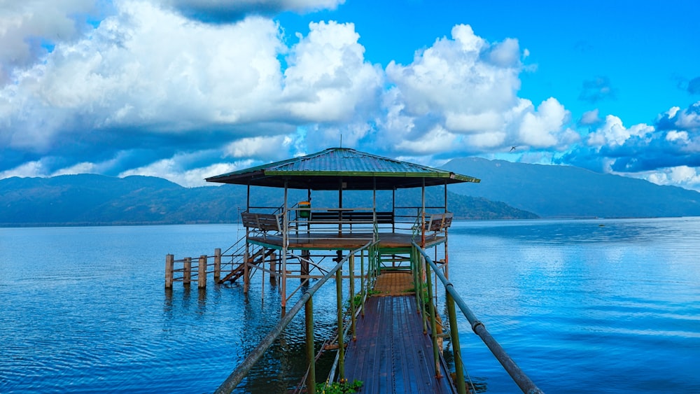 a dock with a covered area over water with mountains in the background