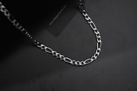 Stacked silver necklaces with subtle motion blur, set on a deep black surface.
