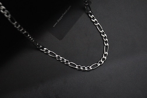Silver chain with a bold, chunky design displayed on a dark background.
