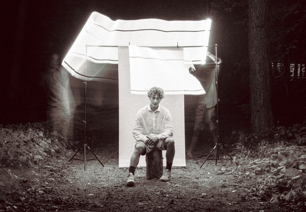 a person sitting on a stool in front of a tent