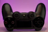 Colorful gaming controller in shades of purple and pink against a dark background.