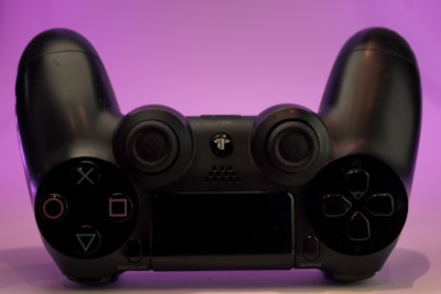 A sleek gaming controller glowing with purple neon light on a dark background.