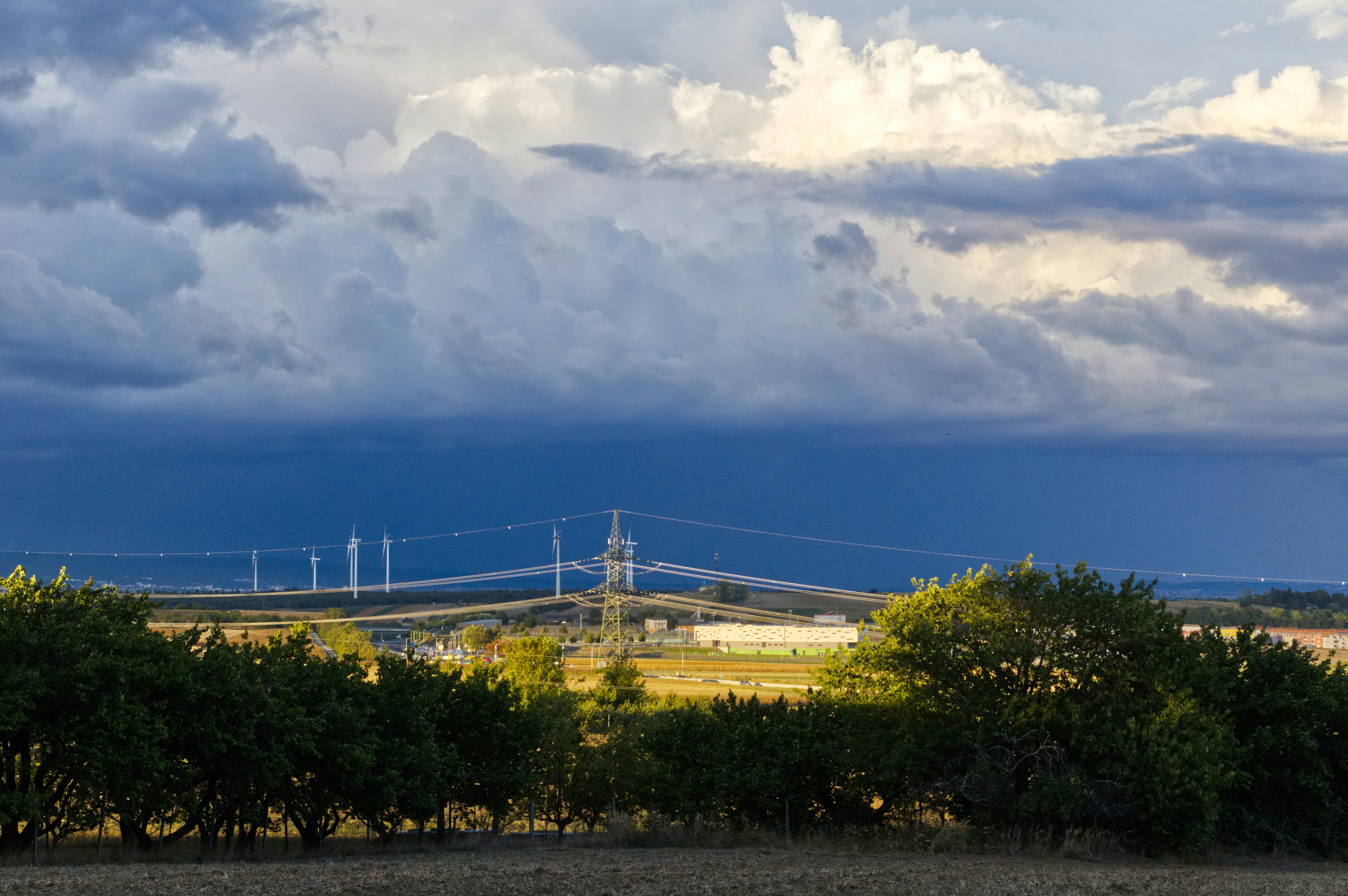 Wind turbines across green landscape under dramatic cloud-filled sky