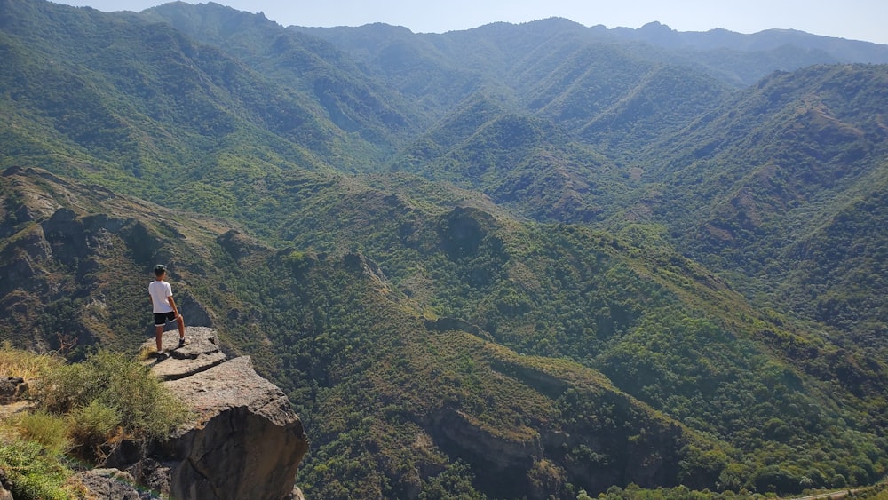Un hombre parado en una roca con vistas a un valle