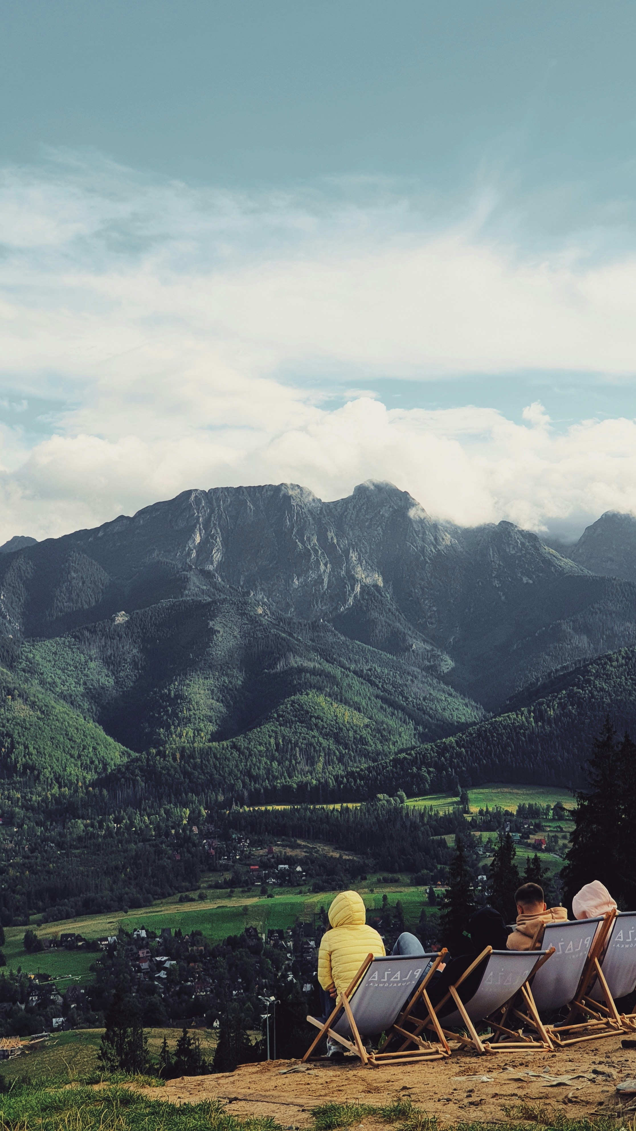 a group of people sitting on a bench in front of a mountain
