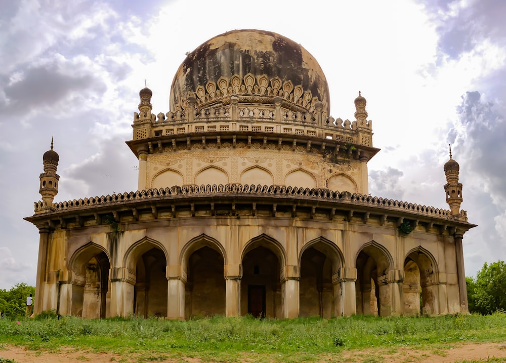 a large stone building with Qutb Shahi tombs in the background