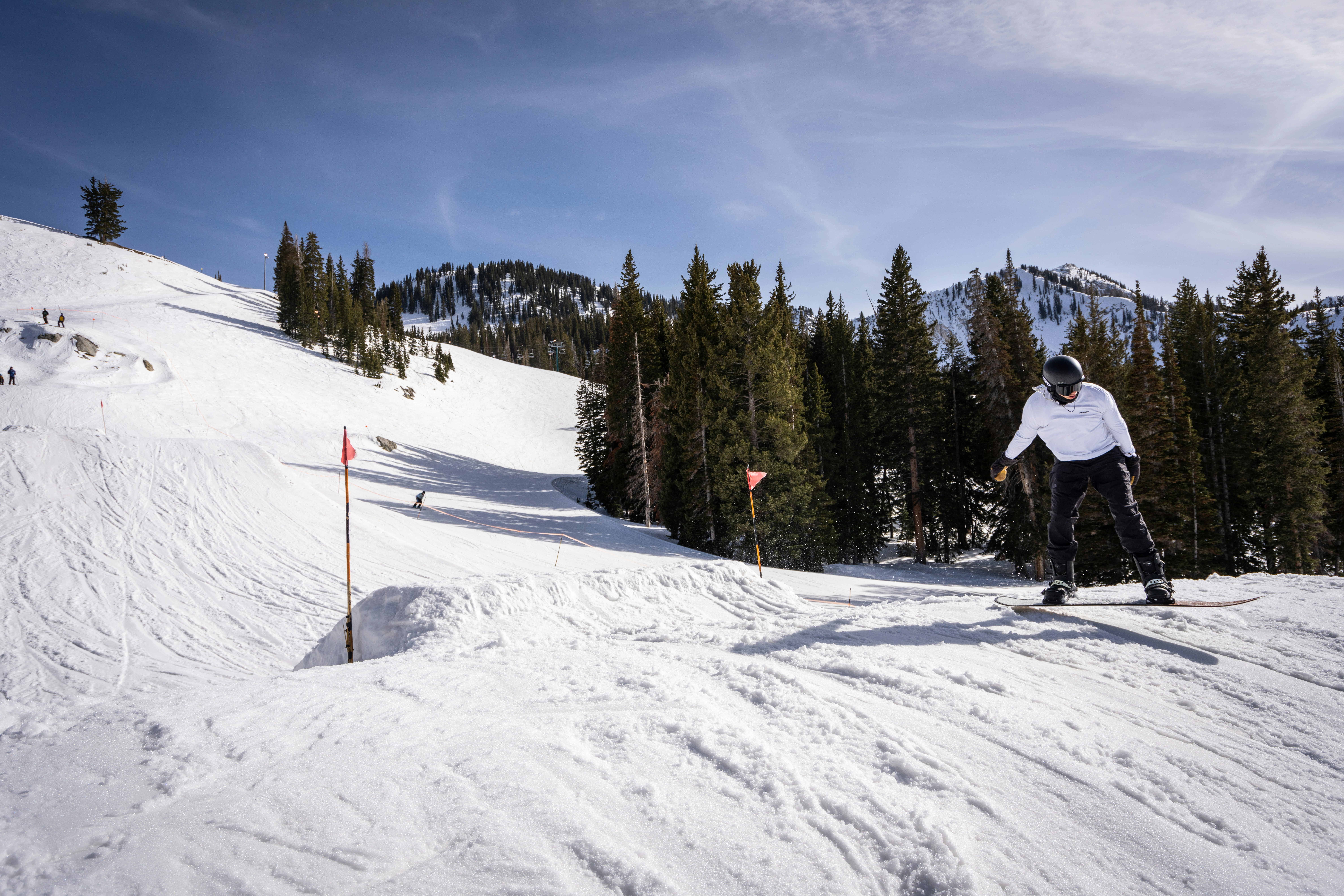a person skiing down a slope, Snowboarder landing trick off jump