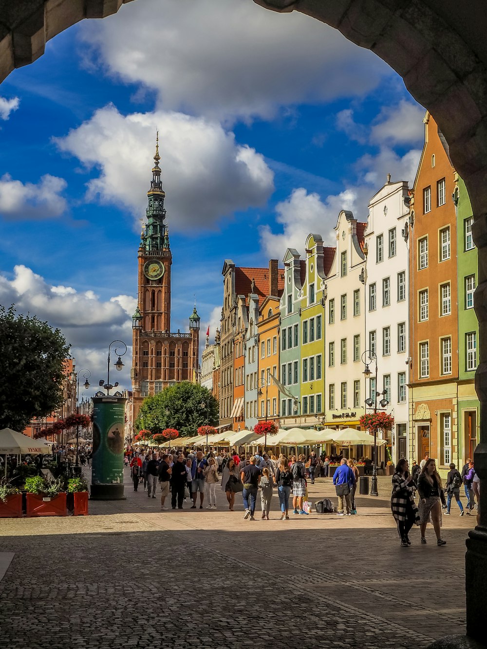 a group of people walking on a street with a tall tower in the background