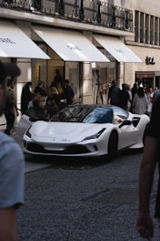 a white sports car parked in a building with people around