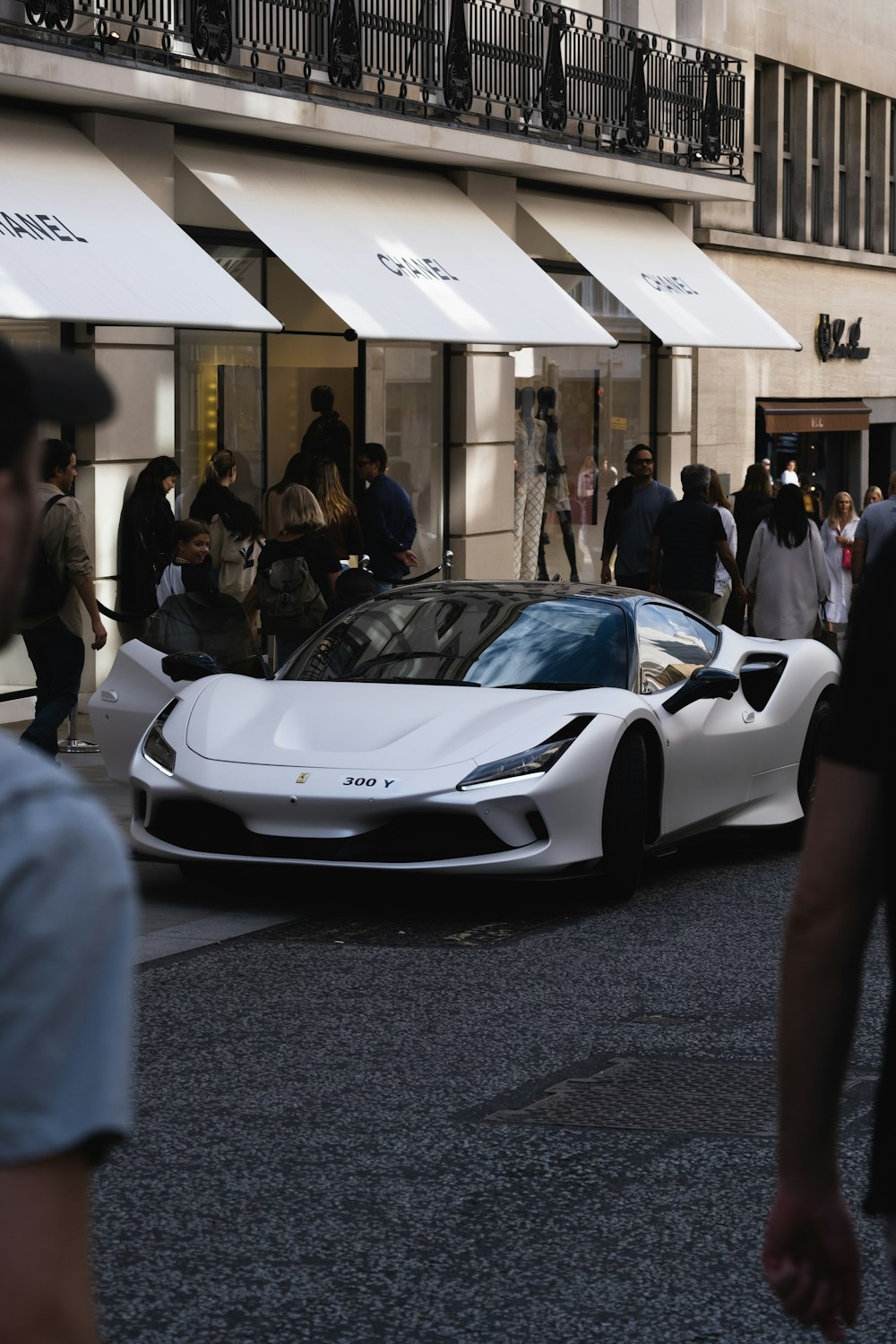 a white sports car parked in a building with people around
